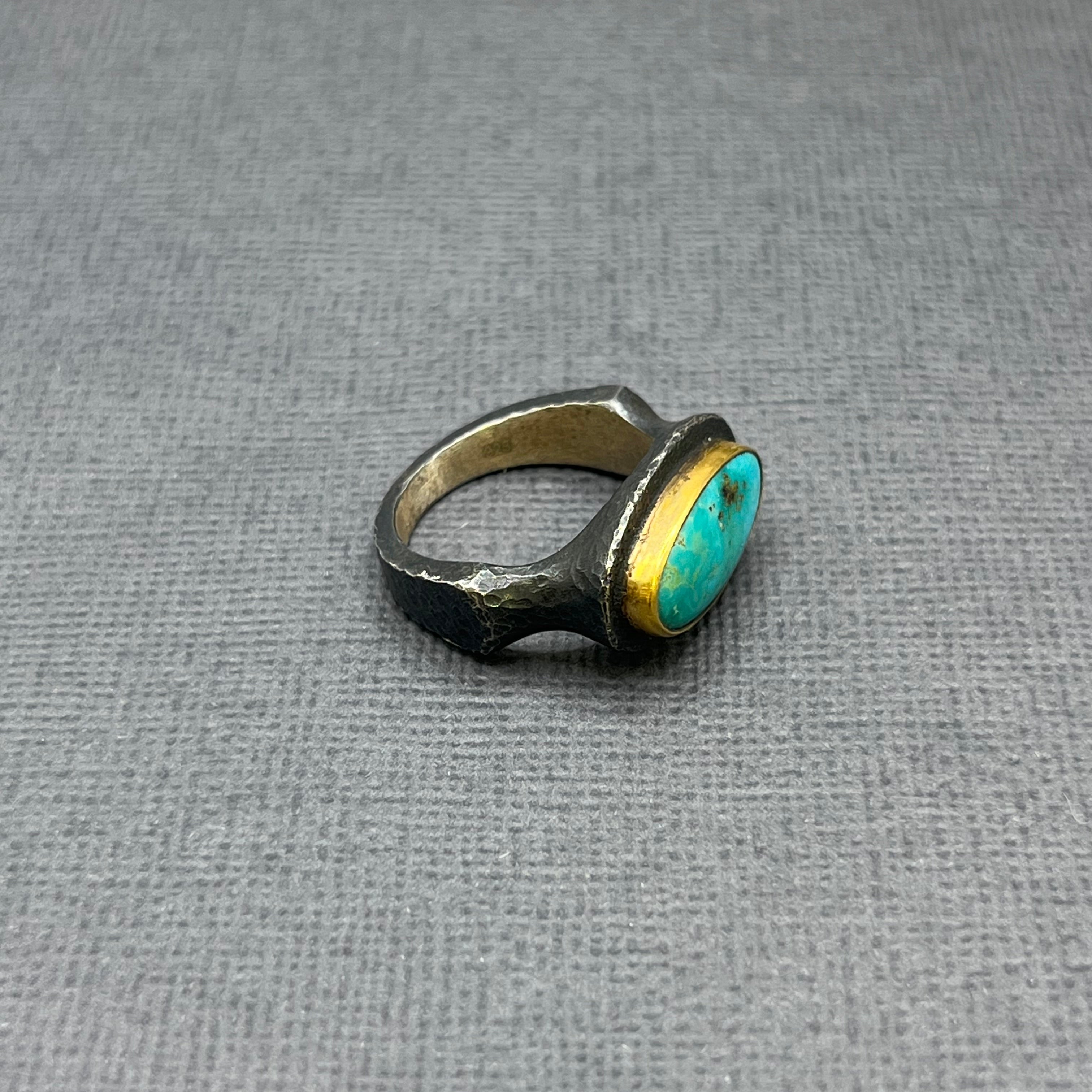 Silver ring with a turquoise stone on a gray textured background