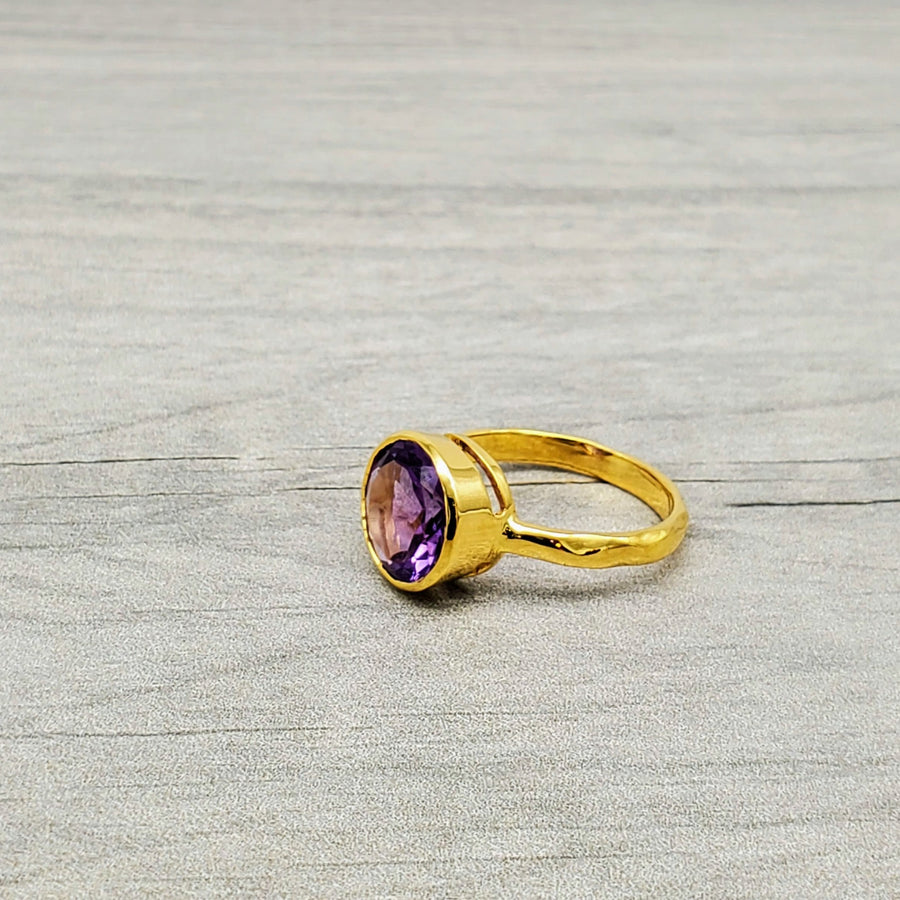 Vibrant round-cut Amethyst Center stone encased in 14k gold and a pounded band. The texture of the band brings in light to enhance the beauty of the stone
14 Kt Yellow Gold
Amethyst
Hand Crafted
available in every size
Round cut